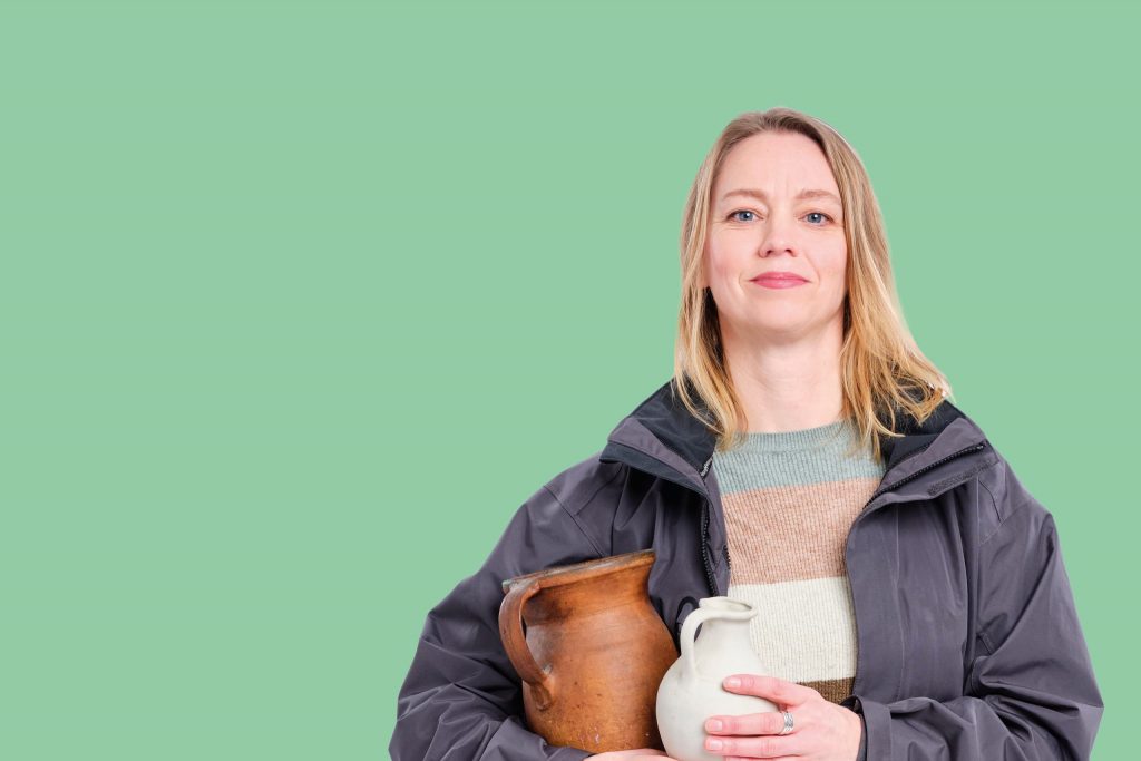 Foto van collega Margriet die archeologische vondsten in handen heeft.