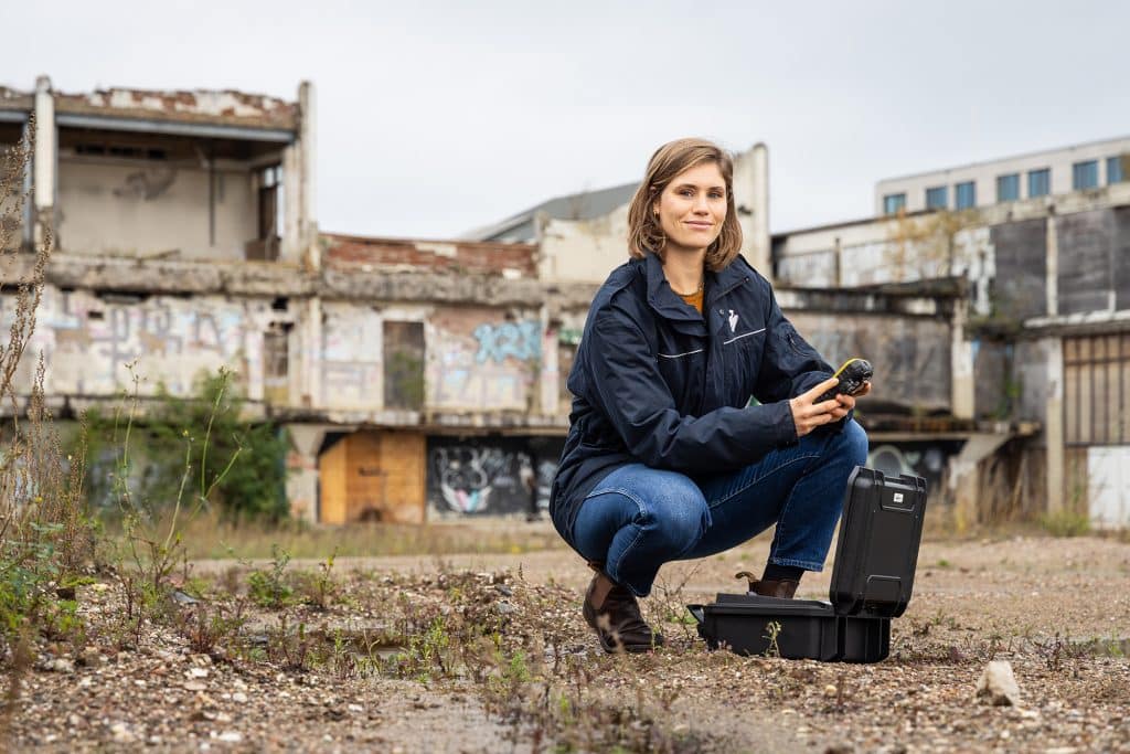 vrouw hurkend op de grond met apparaat vast