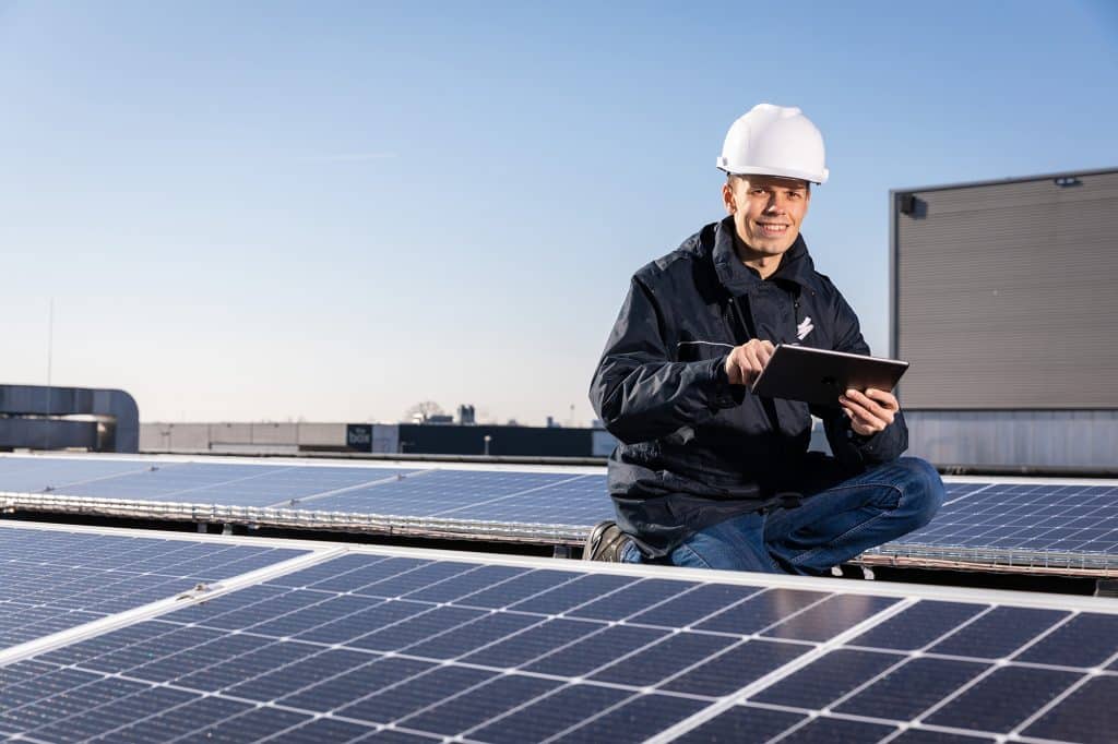 man op dak van zonnepanelen